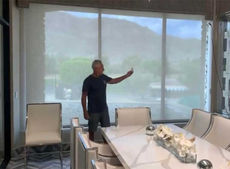 A man showing off remote controlled blinds in a luxurious dining room